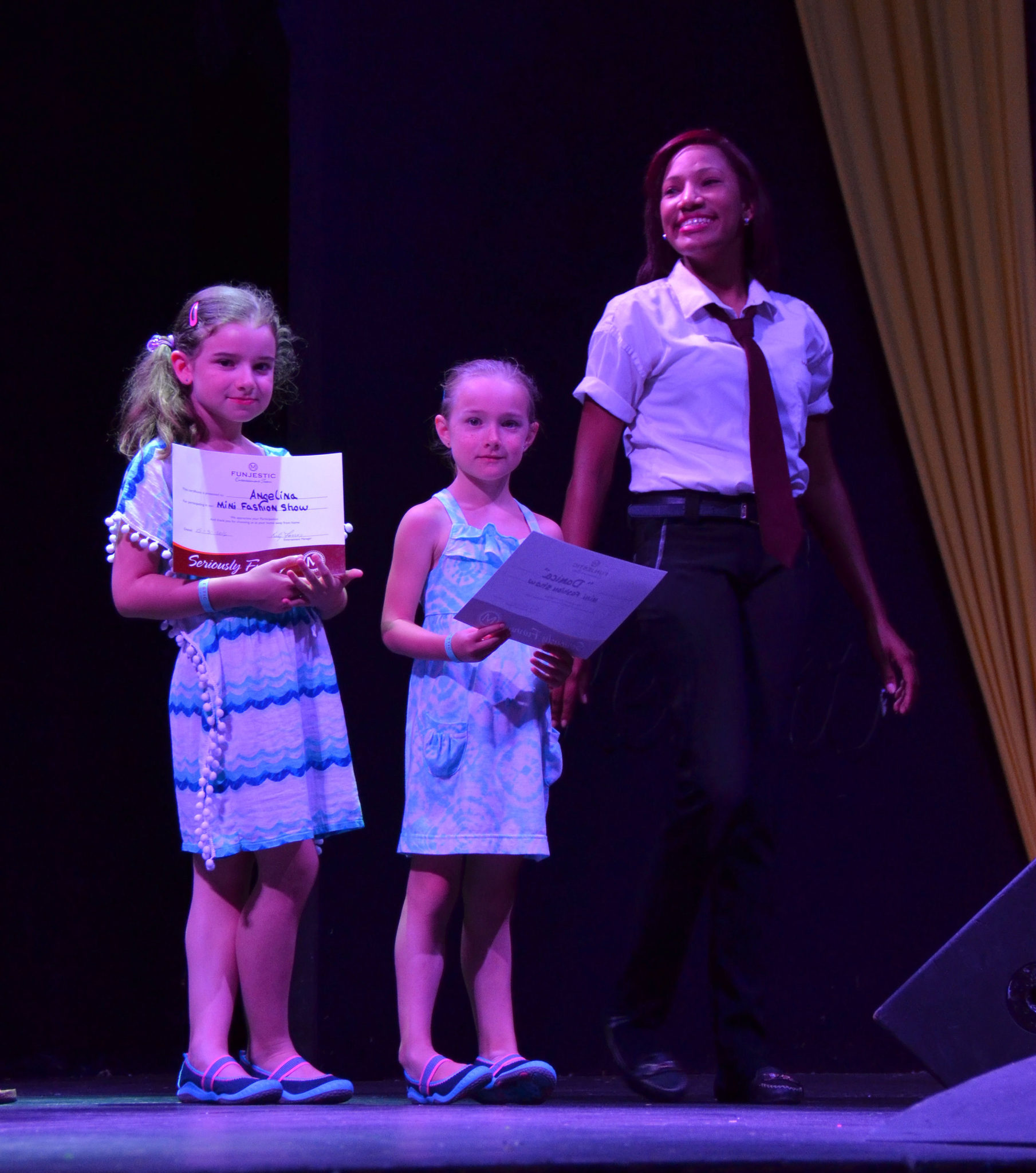 The kids receiving their certificates from the fashion show