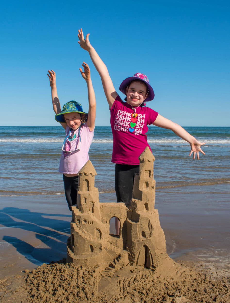 The kids posing with their sandcastle