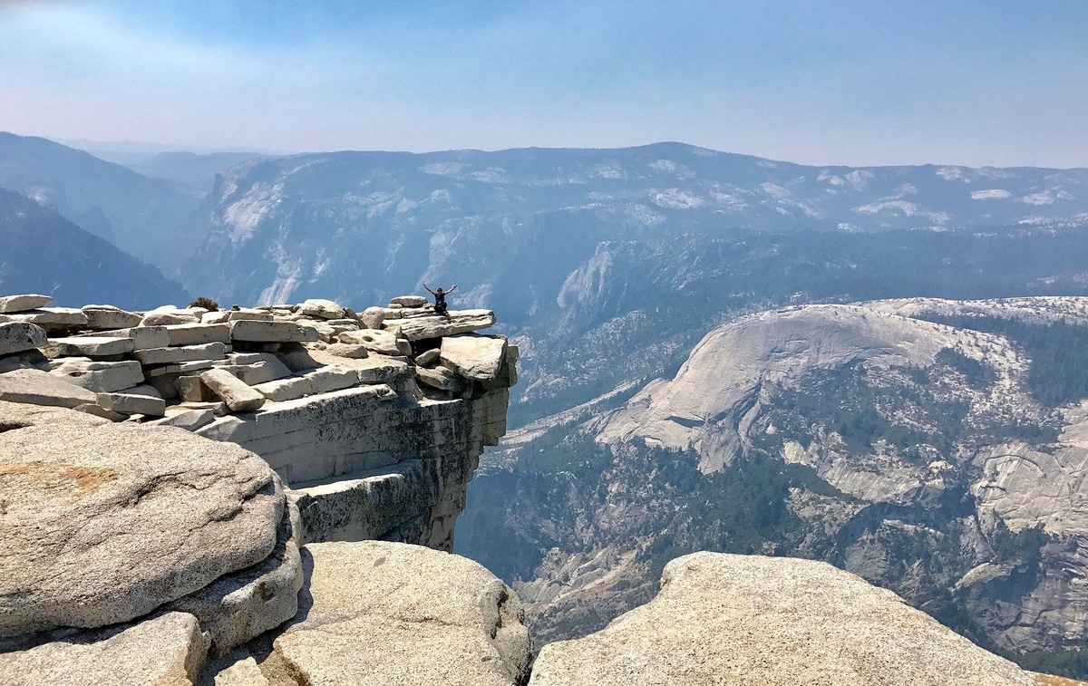 Waving from the top of Half Dome with the Yosemite Valley down below