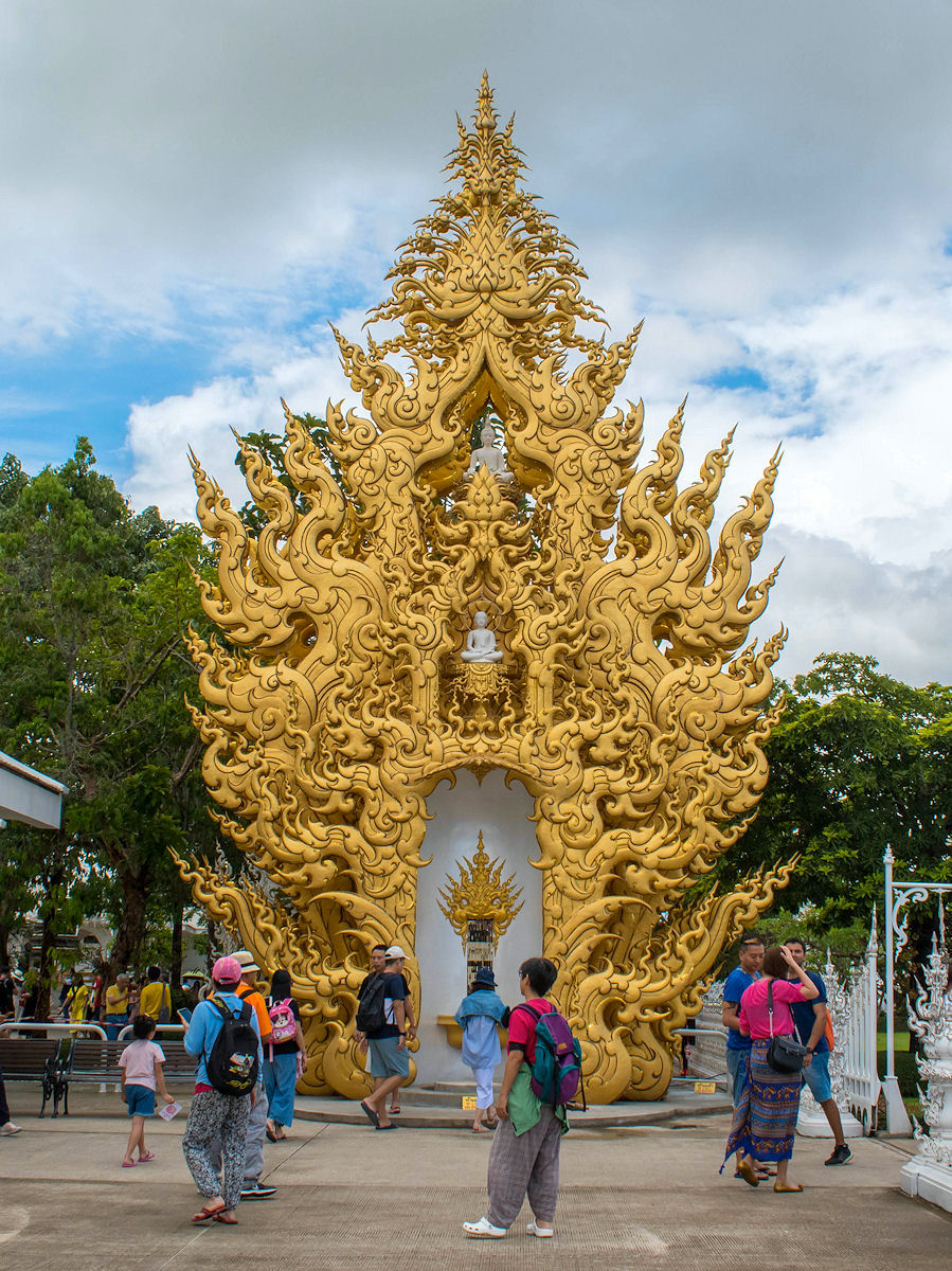 A large golden sculpture with a small white Buddha near the White Temple