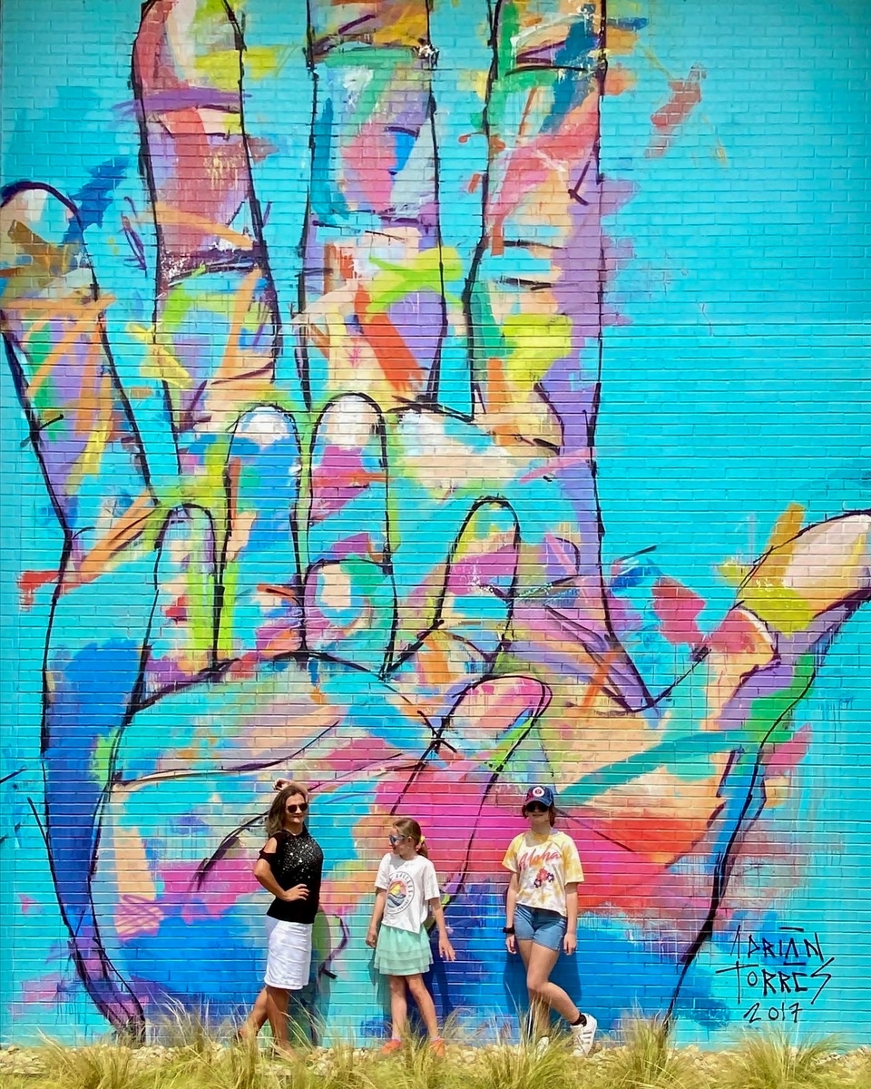 Standing in front of a colorful mural by Adrian Torres at Legacy Central in Plano